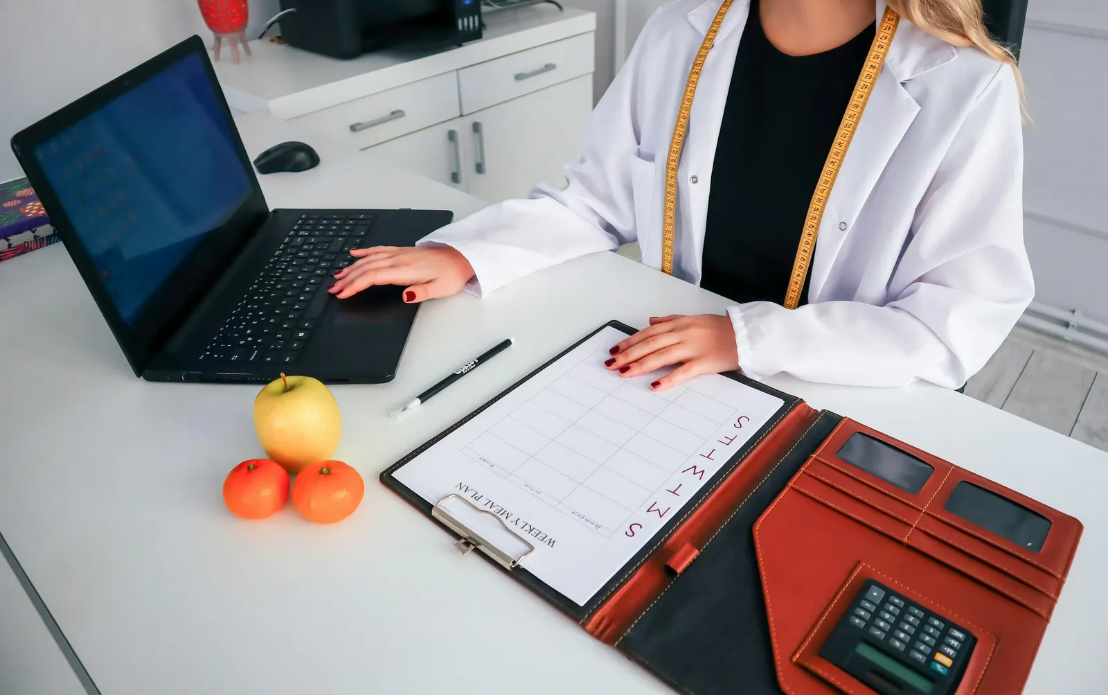 Profesional de la salud trabajando en una laptop junto a una planilla de planificación